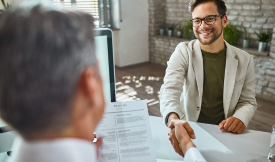 Happy male candidate greeting a member of human resource team on a job interview in the office.