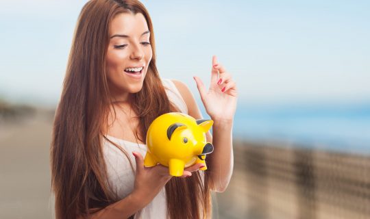portrait of a pretty girl inserting coin in a piggybank